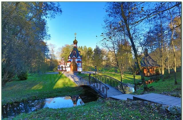 Часовня святого источника с мостиком через пруд в лесу